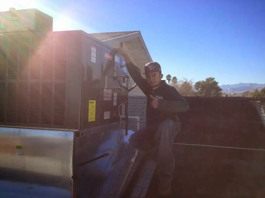 HVAC technician performing AC Tune-Up on a rooftop unit in Maumee